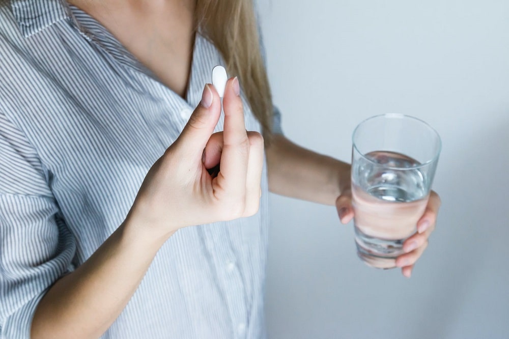 Women taking pill with glass of water