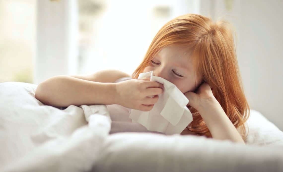 sick young girl blowing her nose
