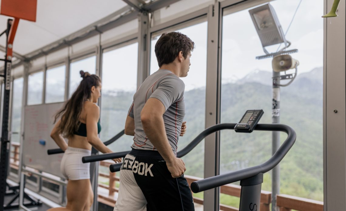 man and woman running next to each other on manual treadmills