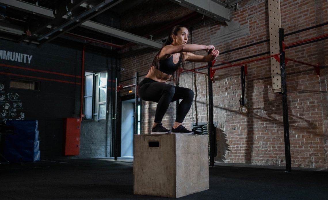 athletic woman jumping on plyo box
