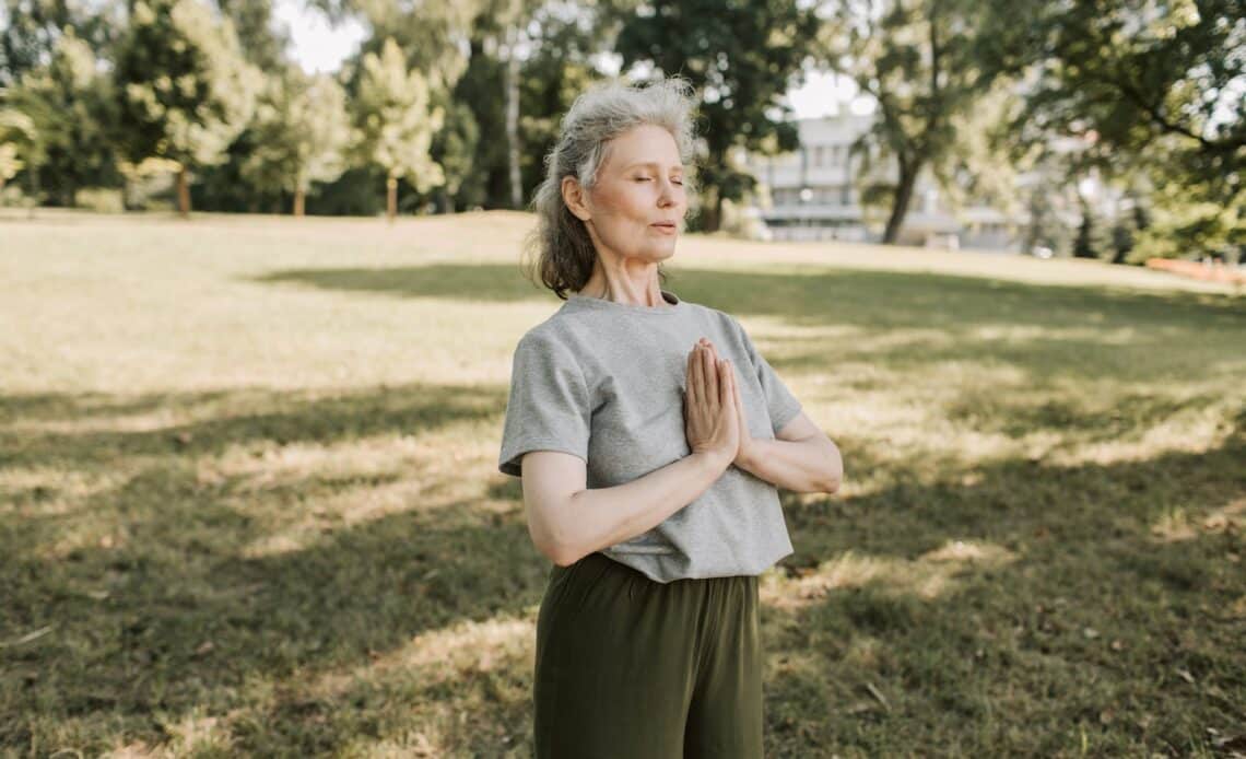 An Elderly Woman in Gray Shirt Meditating at the Park